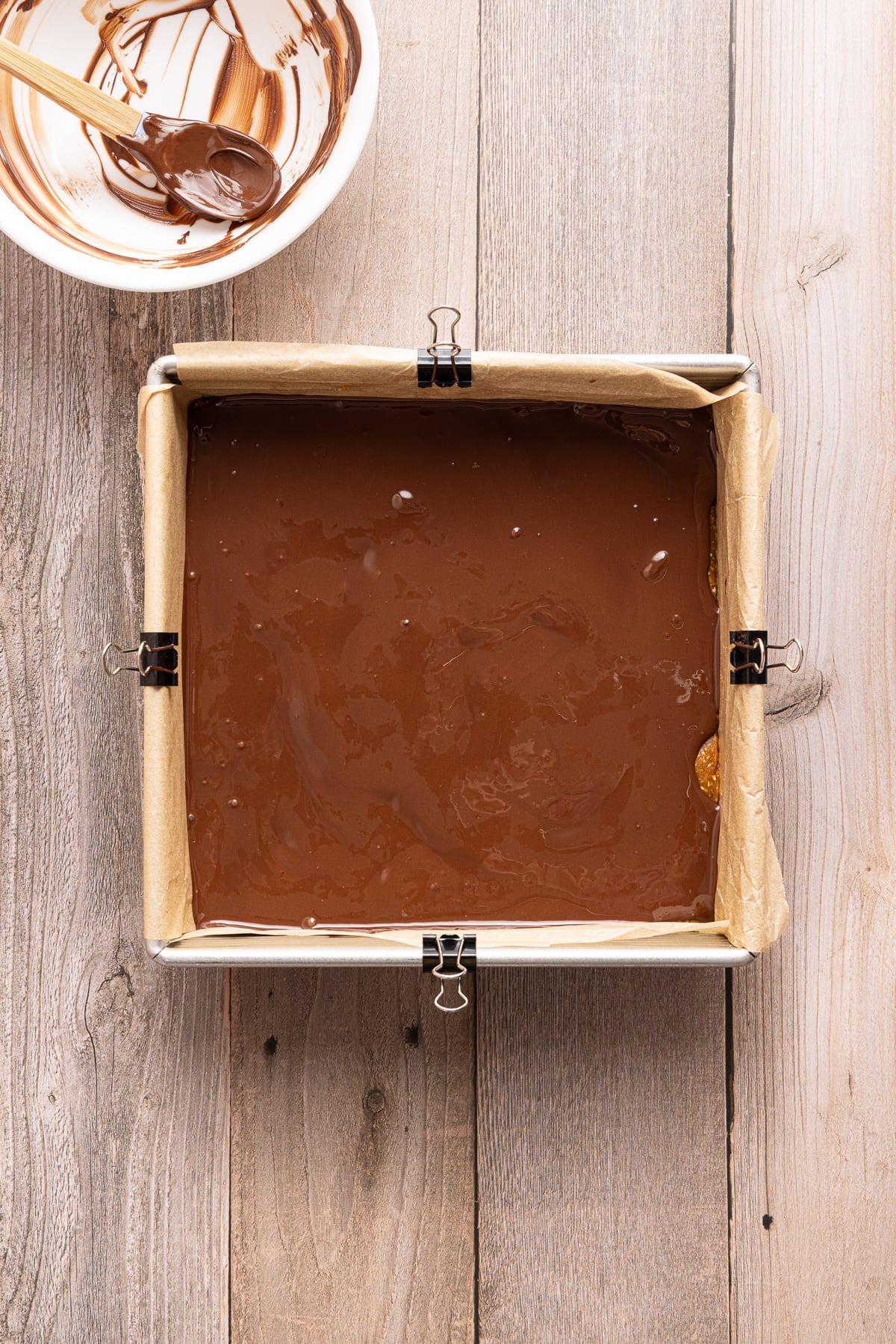 The melted chocolate topping spread over the pumpkin base in the baking pan.