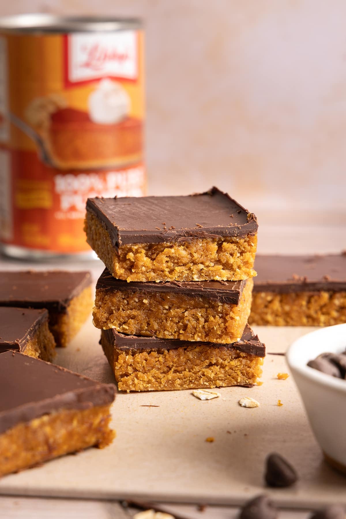 A stack of three No Bake Chocolate and Peanut Butter Pumpkin Oat Bars on a countertop.