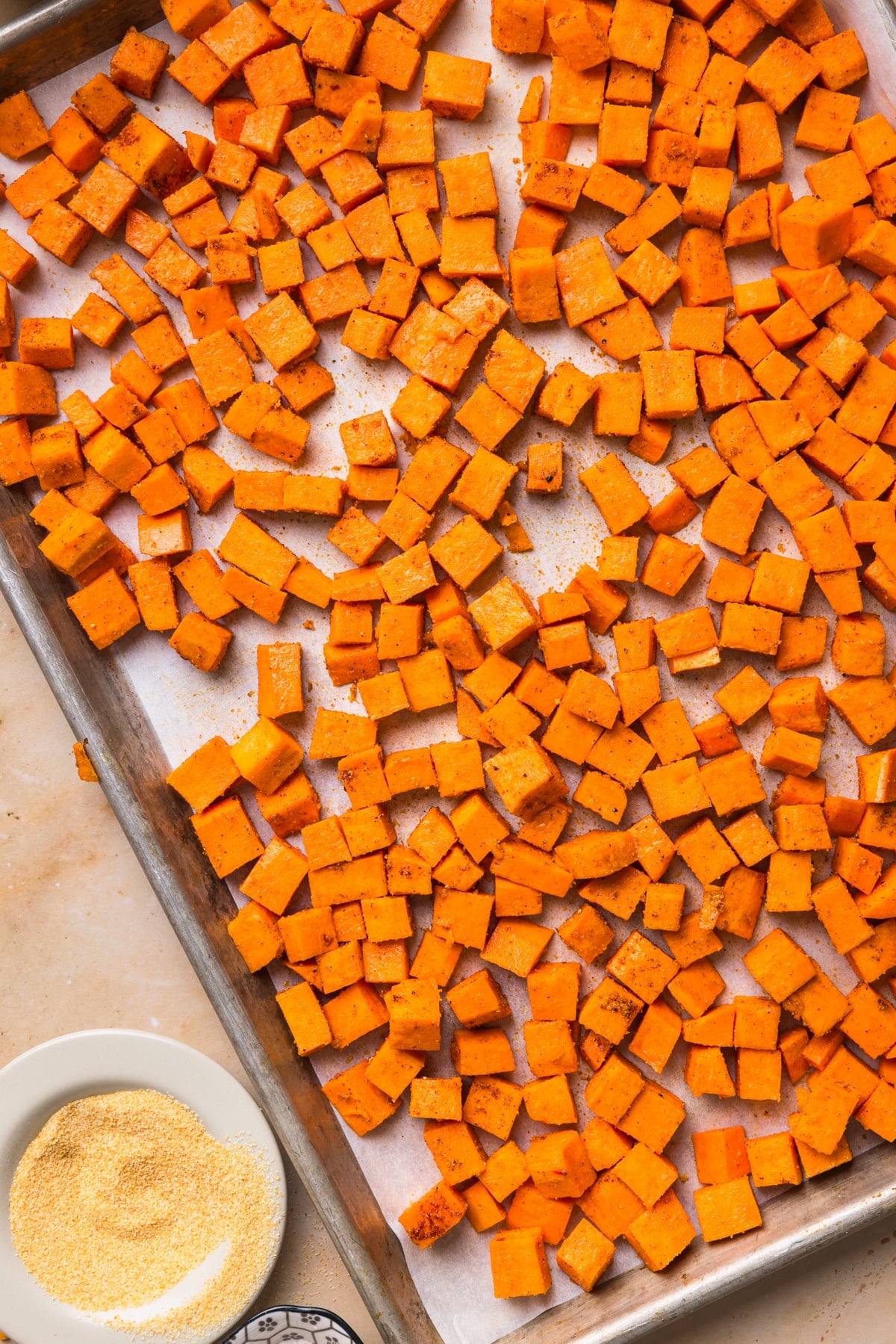 The sweet potatoes cubed on a sheet pan before cooking in the oven.