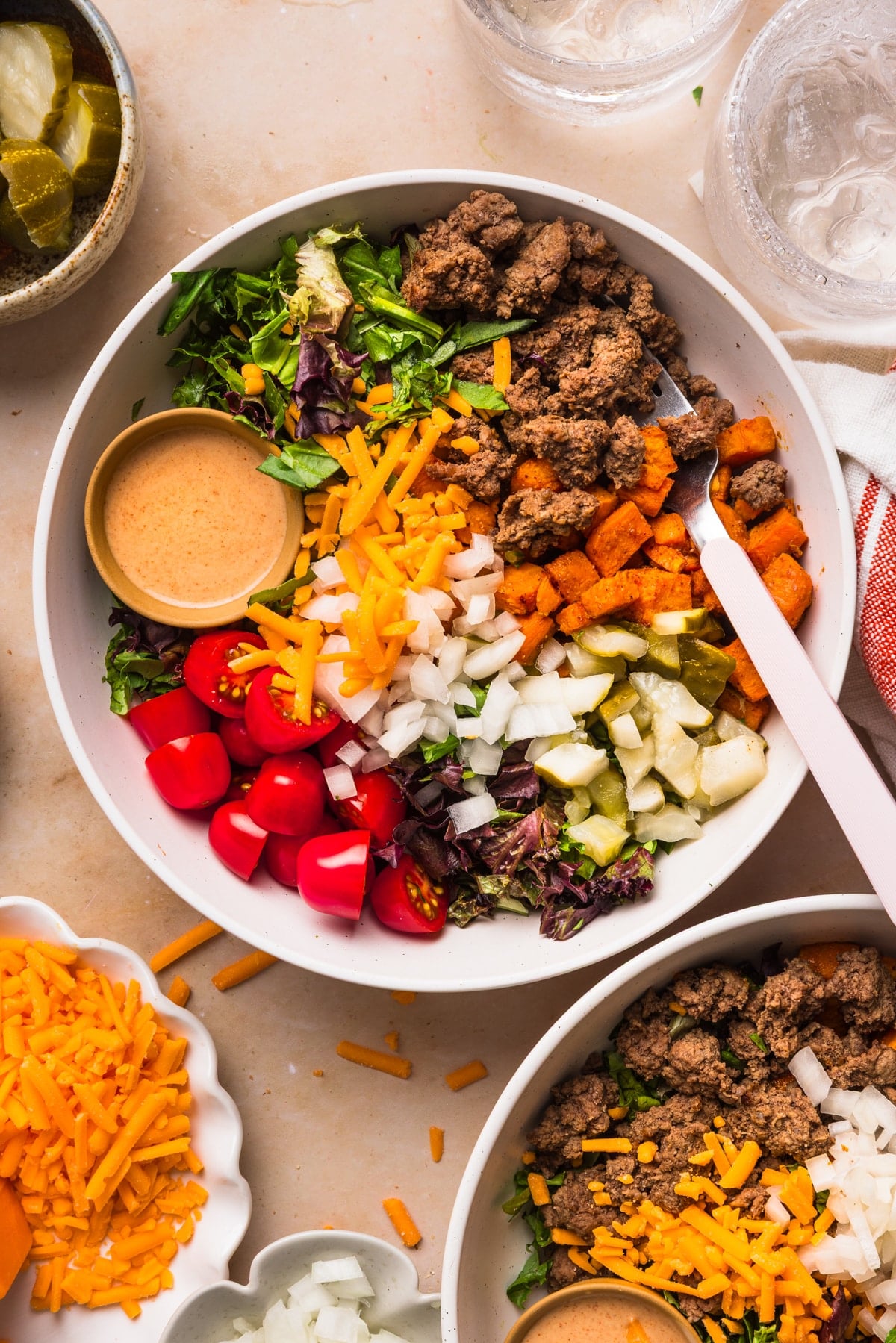 All of the ingredients for the burger bowl in a bowl, including a small bowl of the burger sauce.