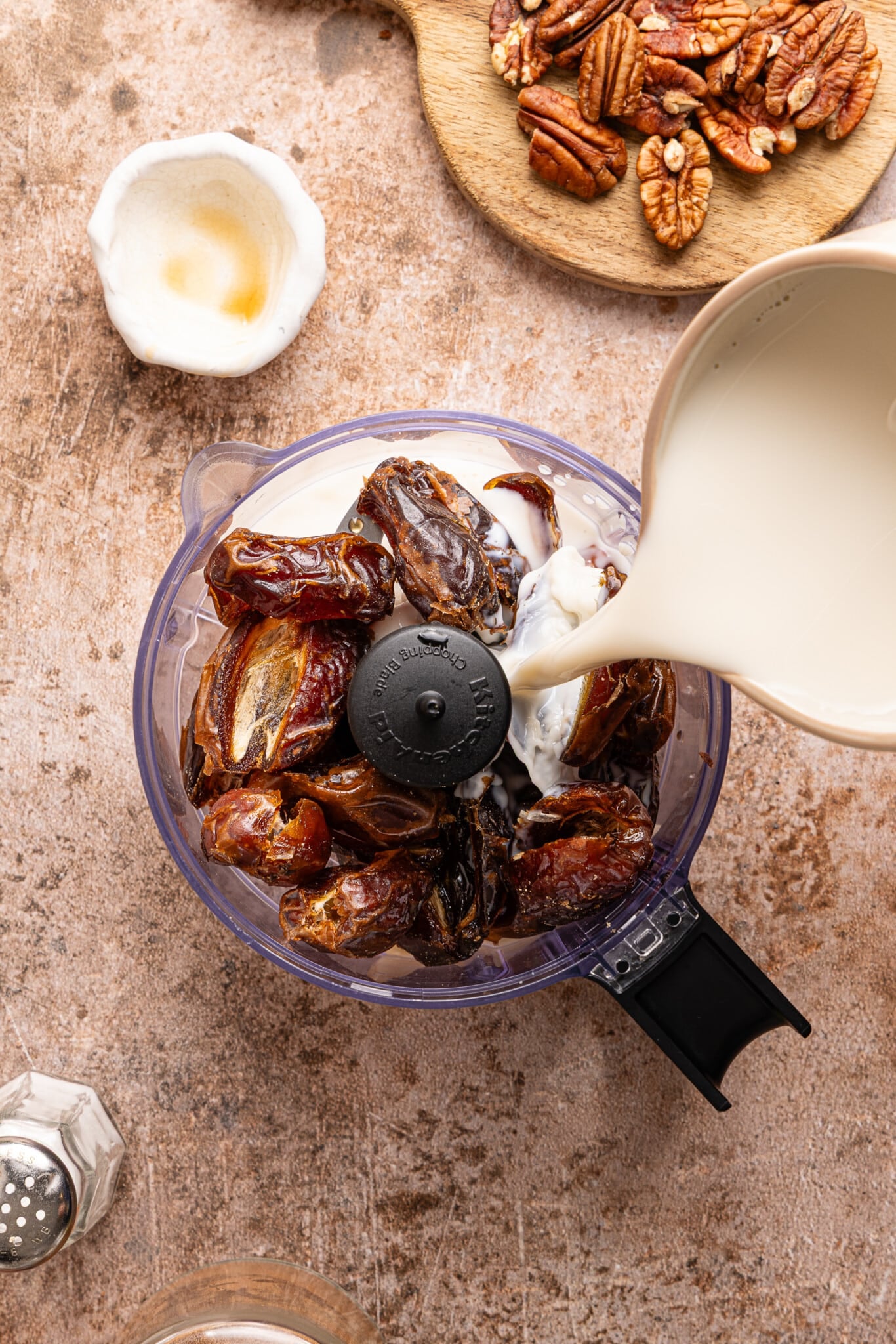 Milk being poured into a food prodcessor with dates.