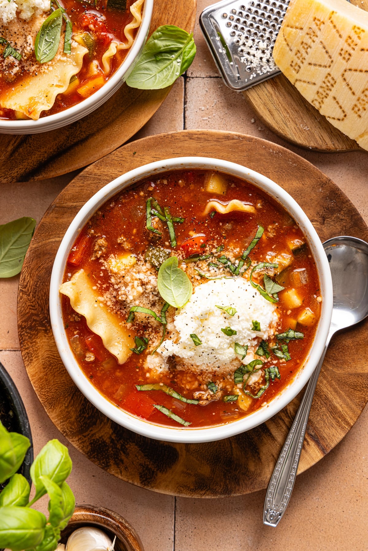 A bowl of slow cooker lasagna soup on a countertop with a spoon on the side.