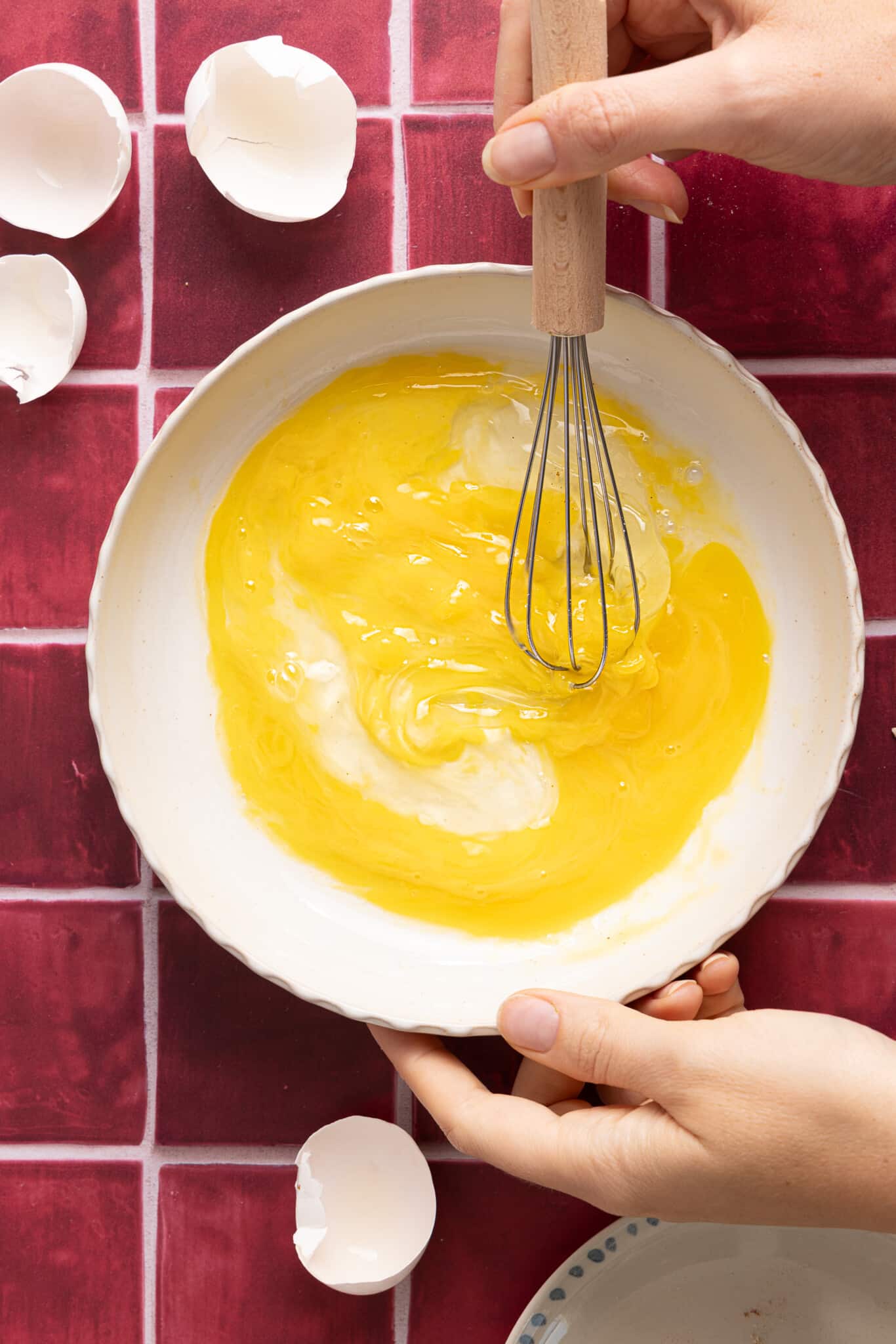 The whisked eggs in a large white bowl.