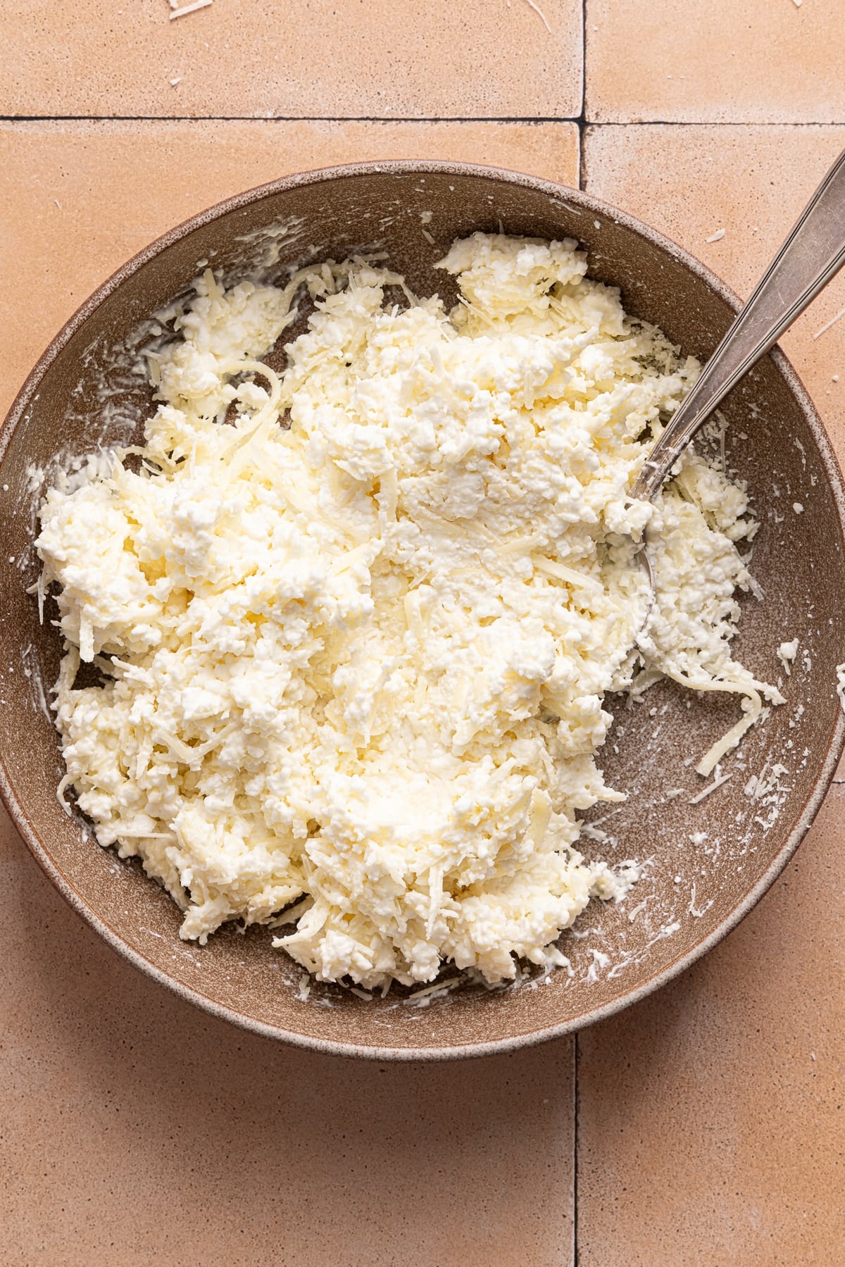 All of the cheeses for the topping mixed together in a large white bowl.