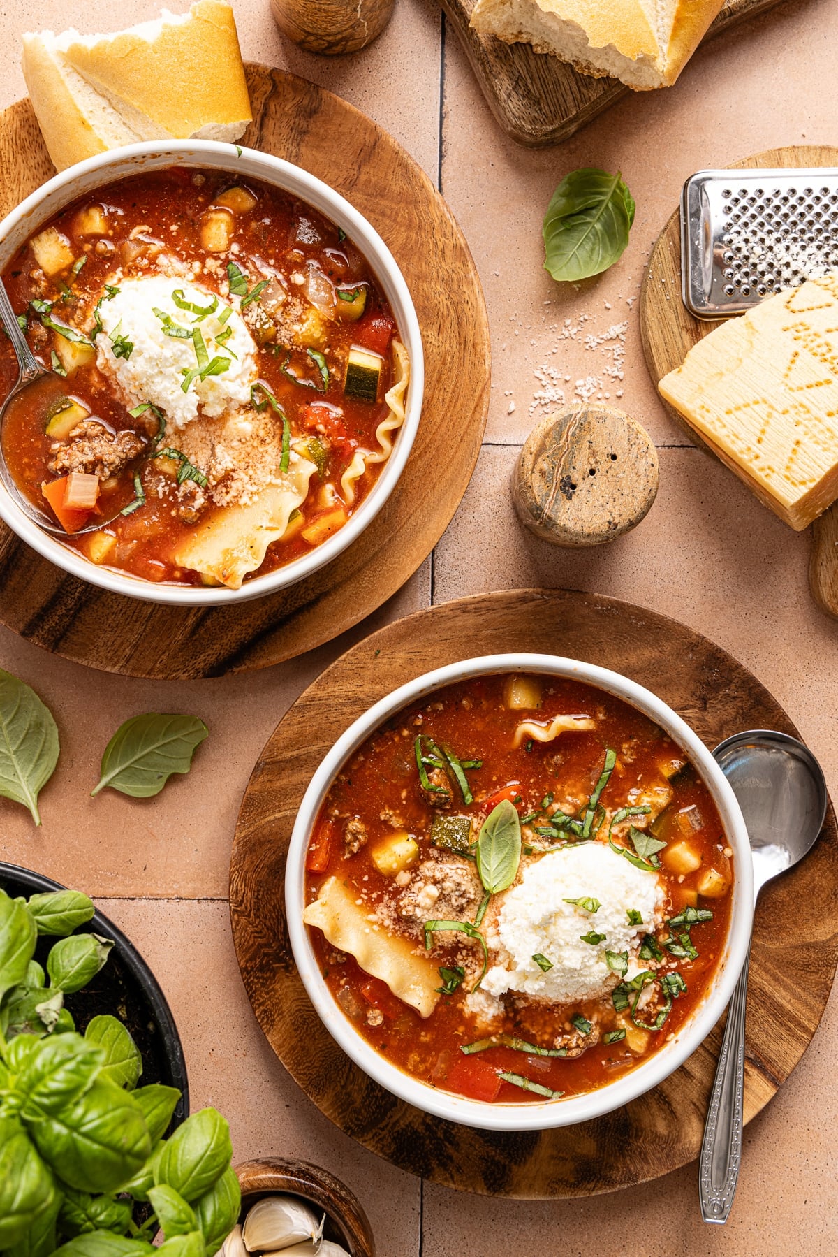 Two bowls of slow cooker lasagna soup on a countertop with the cheese topping.