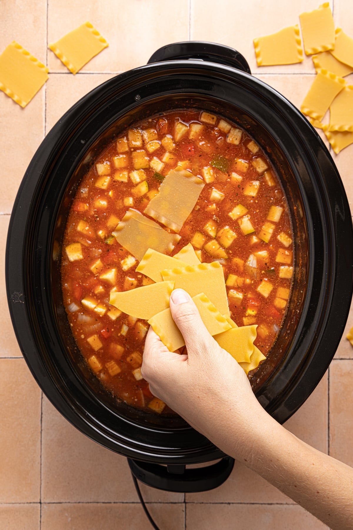 The lasagna noodles in the slow cooker before cooking everything together.